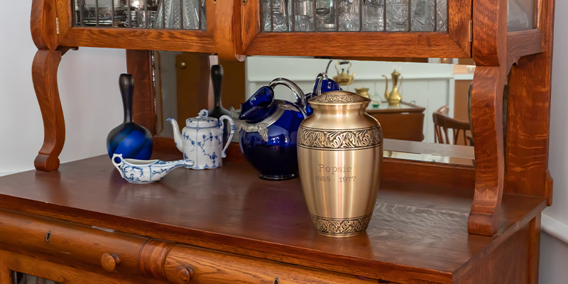 An engraved urn sitting on a desk with a mirror behind it.
